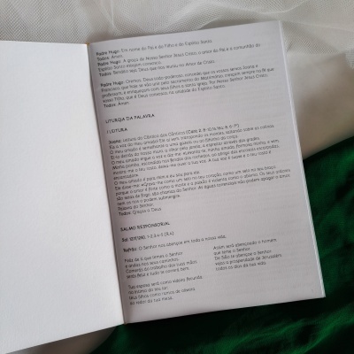 Brochura aberta com texto em português sobre fundo de tecido branco e verde