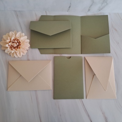 Envelopes e cartões bege e verde com textura sobre superfície de mármore