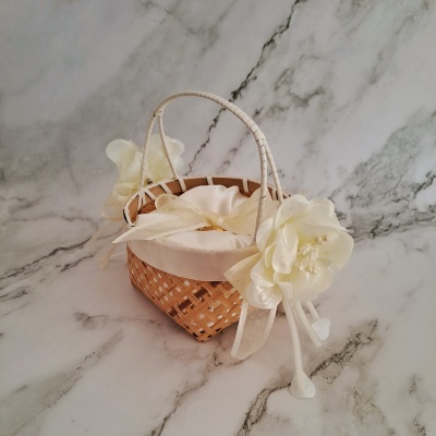 Cesta pequena de vime decorada com flores e laço branco sobre fundo mármore