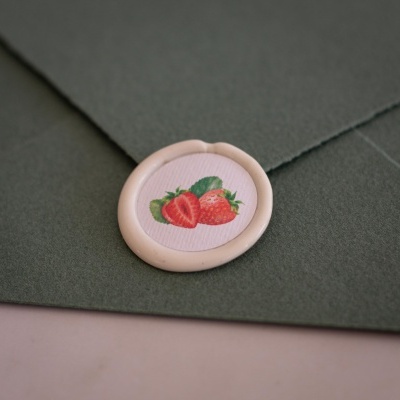 Envelope verde escuro com selo de cera bege com morangos impressos