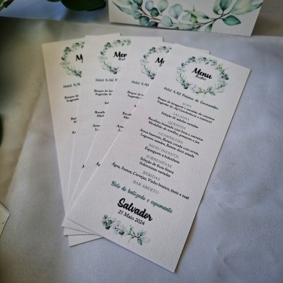 Menus de casamento com design floral verde em papel creme sobre superfície branca