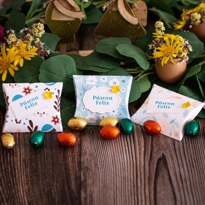 Caixas de presente com design floral e ovos de chocolate sobre mesa de madeira