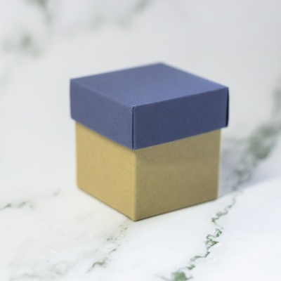 Caixa pequena quadrada com tampa azul e corpo castanho