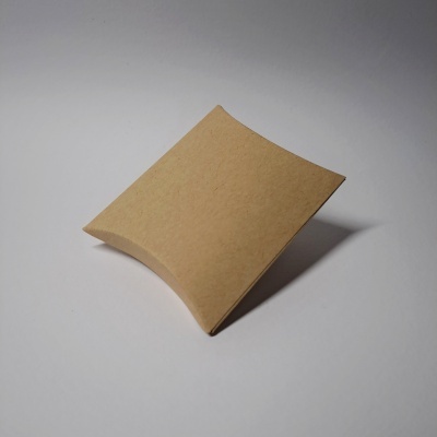 Pequena caixa de cartão castanho claro com formato curvo sobre superfície branca