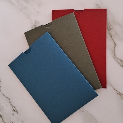 Três envelopes coloridos azul, verde e vermelho sobre superfície de mármore