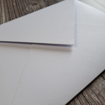 Dois envelopes brancos texturados sobre madeira escura