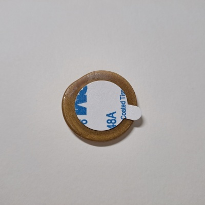 Anel vedante castanho com autocolante branco e azul numa superfície branca