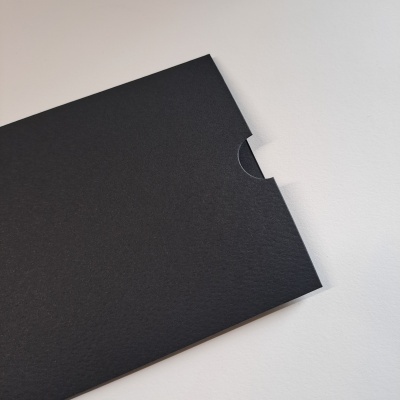 Envelope preto de papel com recorte semicircular em fundo branco