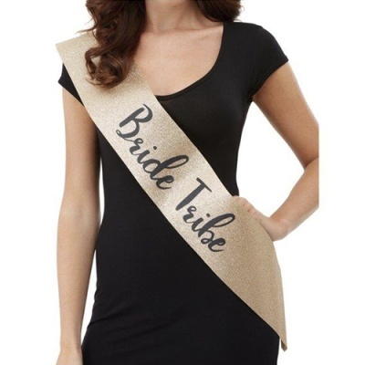 Faixa dourada com texto 'Bride Tribe' usada por mulher com vestido preto