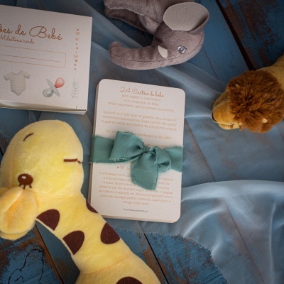 Brinquedos de pelúcia para bebé com cartão e caixas sobre madeira azul e tecido azul claro