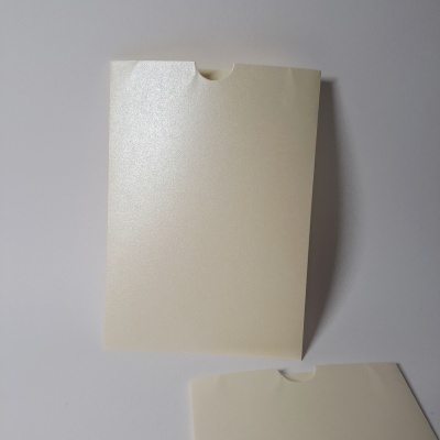 Envelope branco perolado com fecho arredondado sobre superfície branca