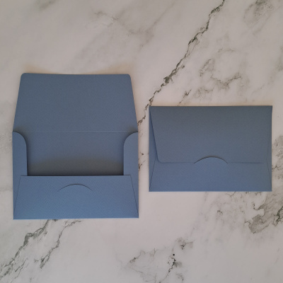 Dois envelopes azuis em papel texturizado em superfície de mármore
