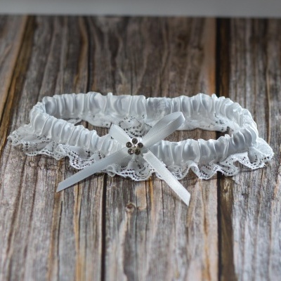 liga de noiva branca em tecido elástico com renda e laço, sobre superfície de madeira