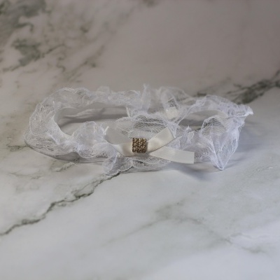 Liga branca de renda com fita e detalhe em strass sobre marmore claro