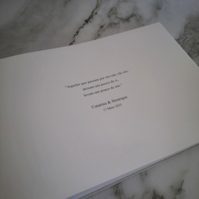 Livro ou caderno branco com texto a preto no centro da página sobre superfície de mármore