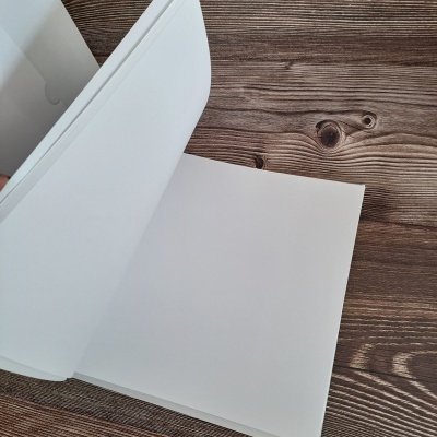 Bloco de folhas brancas retangulares sobre madeira escura com textura