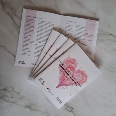 Brochuras sobre casamento com coração rosa na capa, textos em português e inglês, sobre superfície de mármore.