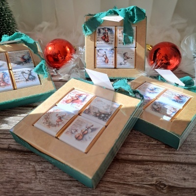 Conjunto de chocolates de Natal em caixas de papel kraft com fita verde e bolas de Natal vermelhas.