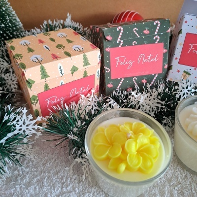 Caixas de presente natalinas com velas decorativas e ramos verdes com neve artificial