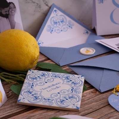 Envelope azul com selo, cartão decorativo azul, limão amarelo e itens sobre mesa de madeira
