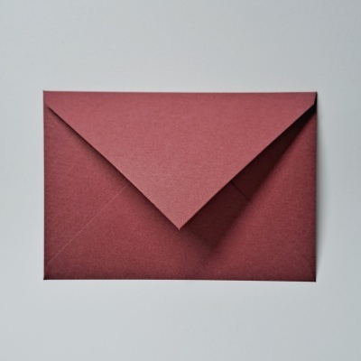 Envelope vermelho escuro sobre superfície branca
