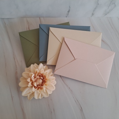 Envelopes de papel coloridos e uma flor sobre superfície de mármore.