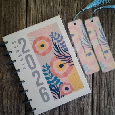 Planner 2026 com design floral e dois marcadores de página sobre madeira