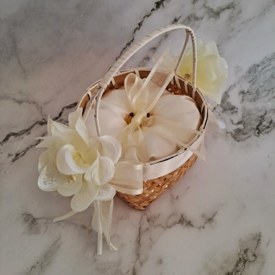 Cesta pequena em vime com almofada branca e flores artificiais brancas.