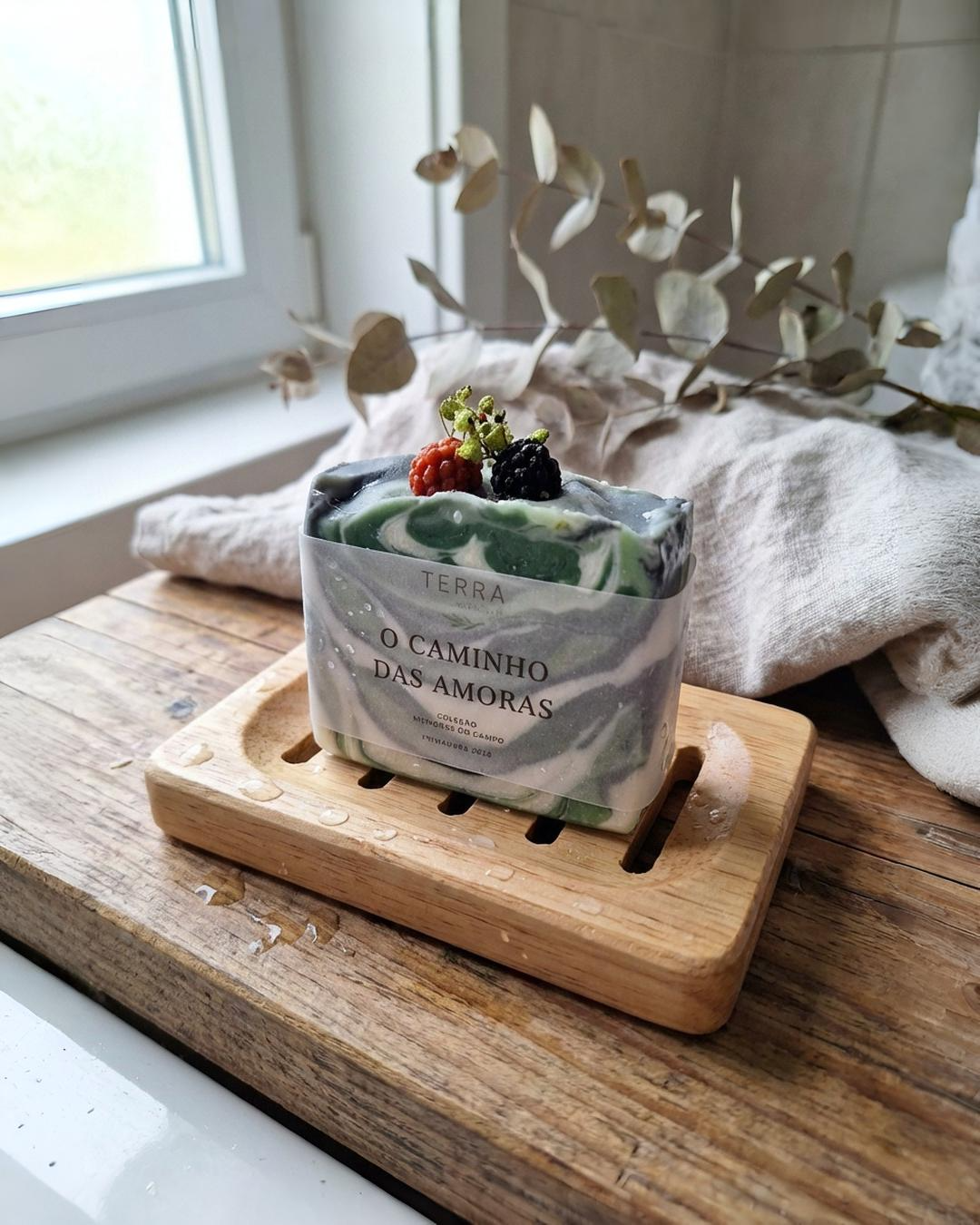 Sabonete Artesanal Natural com Frutas Sabonete artesanal com amoras decorativas sobre suporte de madeira próximo de janela.