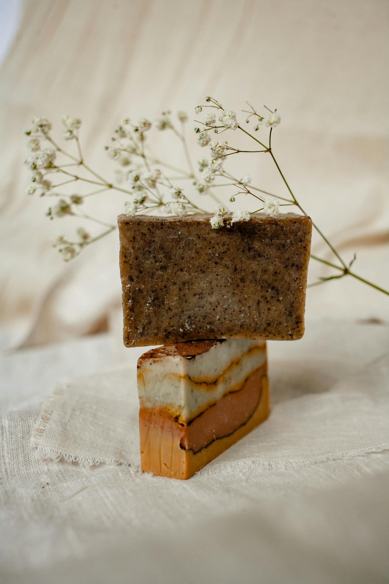 Dois sabonetes empilhados com flores brancas ao fundo