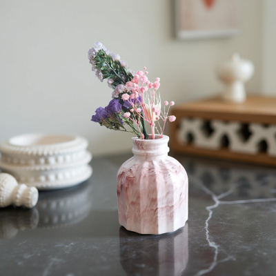 Vaso de cerâmica marmoreado com flores secas sobre superfície preta