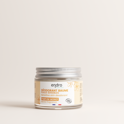 Frasco pequeno de desodorizante Endro com tampa prateada e rótulo bege sobre fundo claro com decoração floral seca