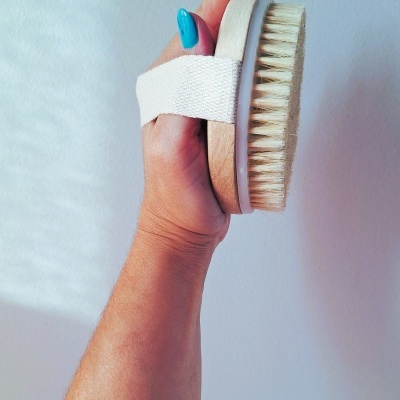Escova corporal de madeira com cerdas brancas e pega em faixa elástica branca