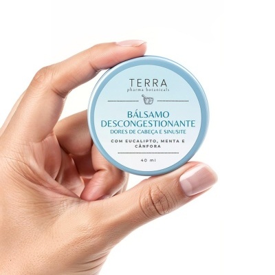 Mão segura recipiente azul claro com rótulo de bálsamo descongestionante