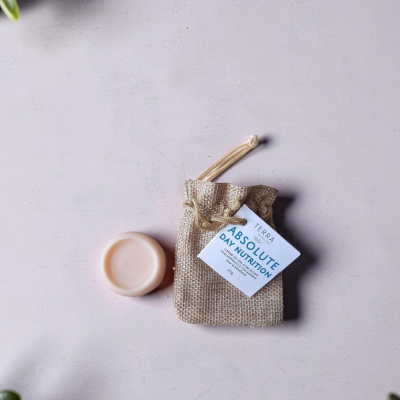 Creme facial sólido cor de rosa pálido e saco de tecido rústico bege com etiqueta ABSOLUTE DAY NUTRITION.
