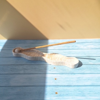 Incensário de pedra clara com bastão de incenso em superfície de madeira azul clara