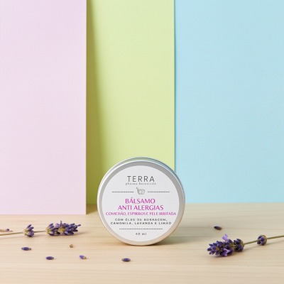 Bálsamo anti alergias em frasco metálico redondo com flores de lavanda em fundo colorido pastel