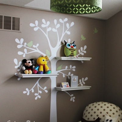 Prateleiras com peluches e decoração de parede com árvore branca sobre fundo cinza