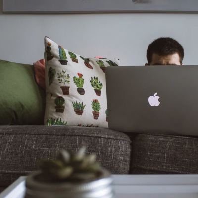 Computador portátil Apple num sofá com almofadas coloridas em sala