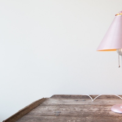 Candeeiro de mesa com abajur cor de rosa sobre mesa de madeira