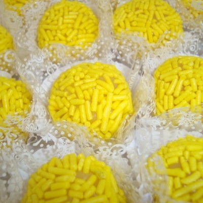 Doces redondos com granulados amarelos em forminhas rendadas brancas