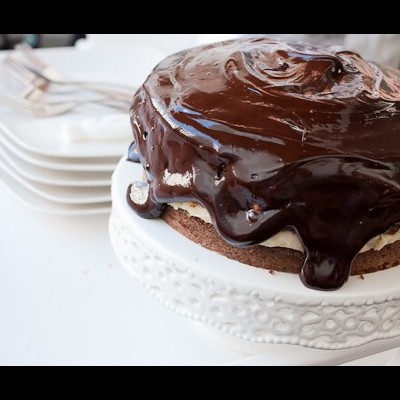 Bolo com cobertura de chocolate num prato branco decorativo