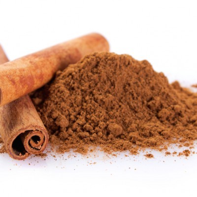 Pauzinhos de canela e pó de canela sobre superfície branca