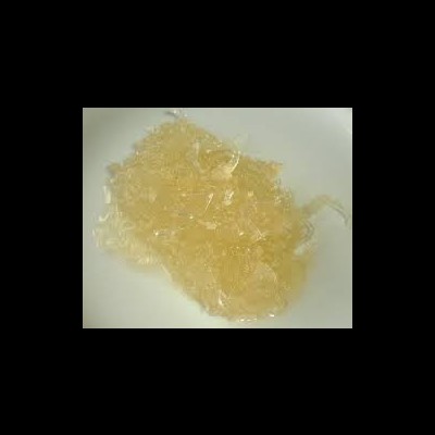 Gelatina translúcida amarelada em pedaços irregulares numa superfície branca