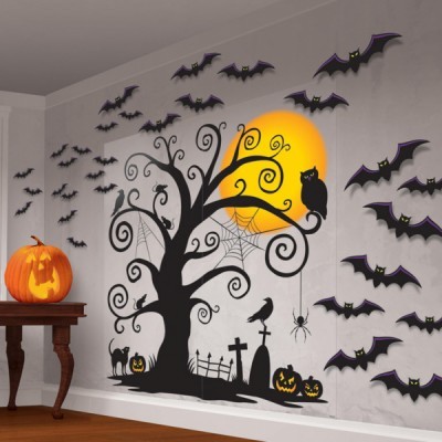 Decoração de parede de Halloween com árvore preta, morcegos, abóboras iluminadas e gato preto junto a uma mesa com abóbora iluminada