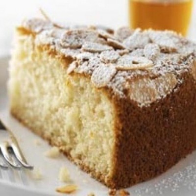 Fatia de bolo com cobertura de açúcar em pó e amêndoas num prato branco