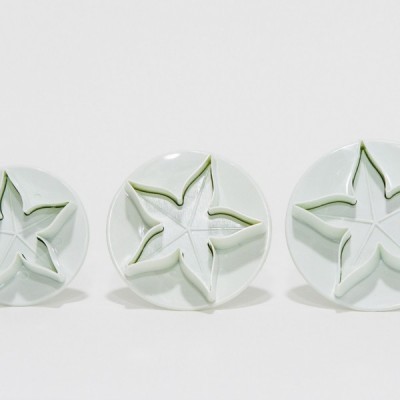 Três pratos brancos com relevo em forma de estrela com contorno verde.