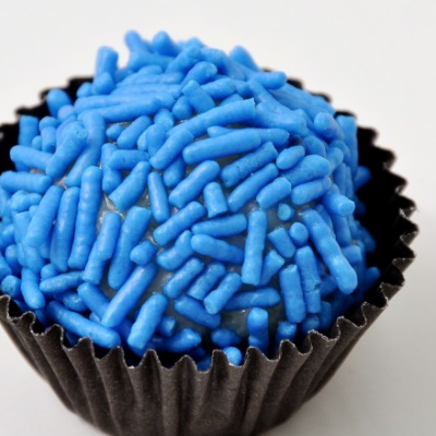 Doce com granulados azuis em forma de bolinha numa forma preta