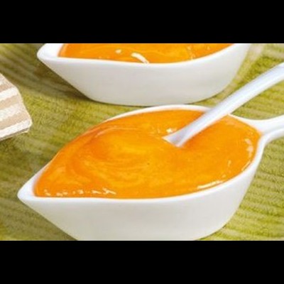 Duas taças brancas com molho laranja e colher em superfície verde