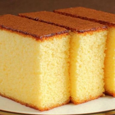 Três fatias de bolo amarelo com cobertura castanha em prato branco com borda preta